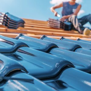 Ryan Construction Systems employee sits on roof and applies shingles