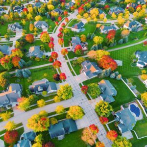 Overhead shot of a suburban Kansas City neighborhood lined with trees in peak fall colors, showcasing homes and winding streets.
