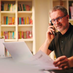 Man looks over paper work while he is on the phone with a Kansas City roofing contractor