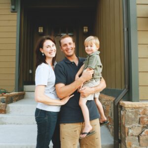 Kansas City family smiling in front of their newly remodeled home with updated siding and gutters.