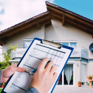 Home inspector holding a checklist in front of a suburban house during a professional roof inspection, preparing the property for fall and winter weather.