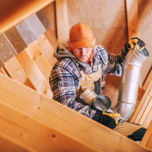 Contractor inspecting attic ventilation system in a wooden roof structure, highlighting proper airflow and insulation for winter roof prep in Kansas City homes.
