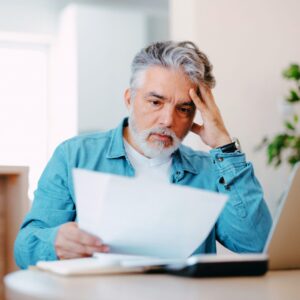 Stressed homeowner reviewing documents, symbolizing the financial burden of unexpected roof repairs due to poor fall maintenance in Kansas City.