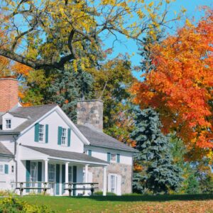 Charming Midwest home surrounded by autumn foliage, highlighting the importance of fall roof inspections before Kansas City’s winter weather arrives.