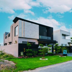 Modern two-story home with a flat roof and sleek exterior design, featuring a manicured lawn and contemporary landscaping in a suburban neighborhood.