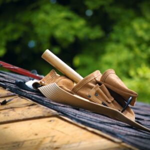 Close-up of roofing tool belt resting on asphalt shingles during a Kansas City home roof replacement project.