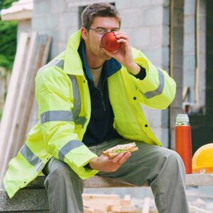 Construction worker in high-visibility jacket enjoying a break on a home remodeling job site in Kansas City.