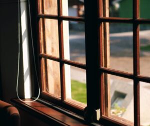 Wood-framed window partially open, letting in sunlight with a pull cord hanging on the side.